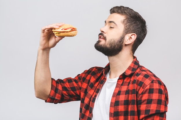 Jovem, segurando um pedaço de hambúrguer. Faça dieta o conceito isolado contra o fundo branco.