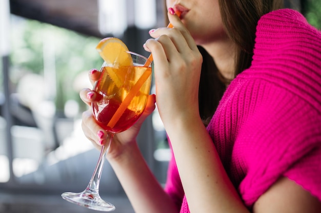 Foto jovem, segurando um spritz de aperol, coquetel, spritz de aperol, em um copo, jovem, em um restaurante, com um spritz de aperol, nas mãos de uma garota, spritz de aperol, coquetel