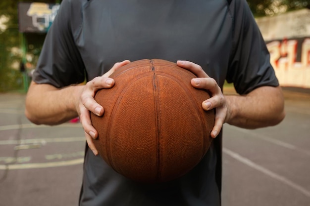 Jovem segurando uma bola de basquete no playground O conceito de estilo de vida ativo esportivo