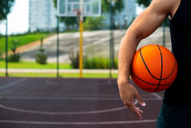 Jovem, segurando uma bola no campo