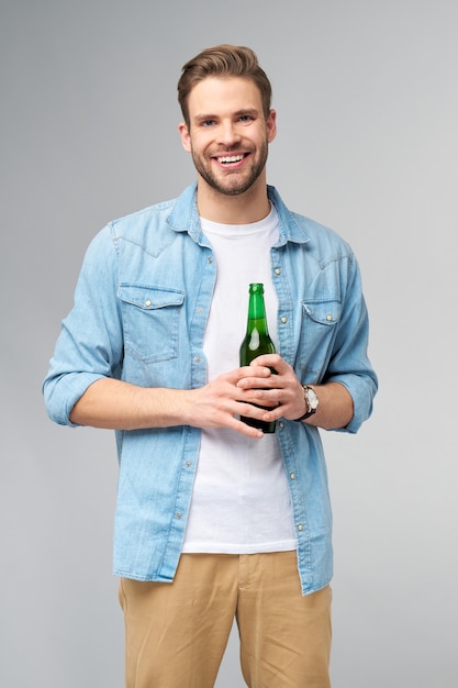 Jovem segurando uma camisa jeans segurando uma garrafa de cerveja em pé