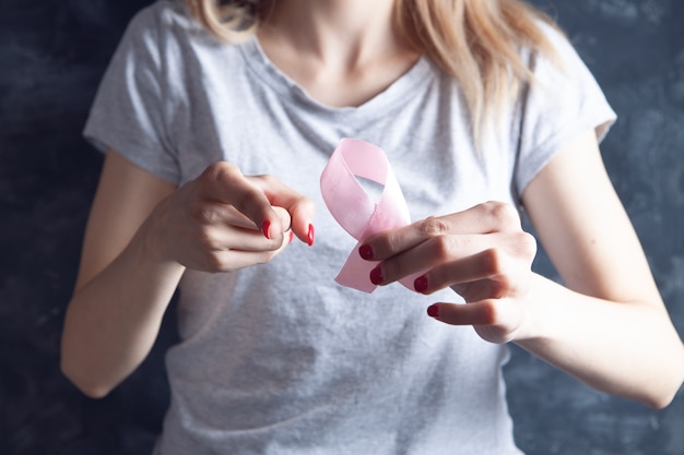 Jovem segurando uma fita rosa e apontando o dedo