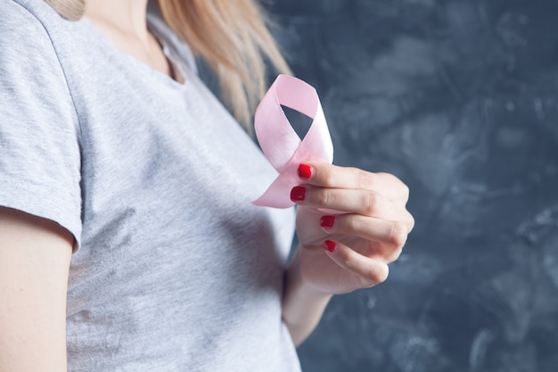 Jovem segurando uma fita rosa