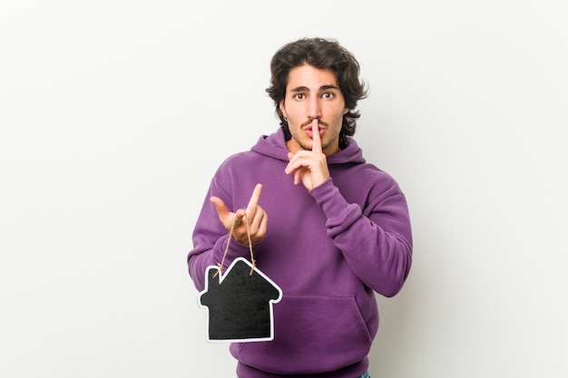 Jovem segurando uma forma de ícone de casa, mantendo um segredo ou pedindo silêncio.