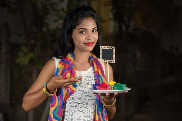 Jovem, segurando uma pequena placa e cor em pó por ocasião do festival de Holi.