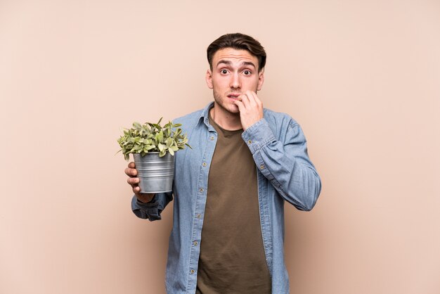 Jovem, segurando uma planta roer unhas, nervoso e muito ansioso