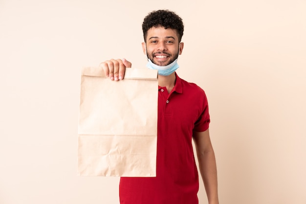 Jovem segurando uma sacola de comida para viagem ___ com expressão feliz