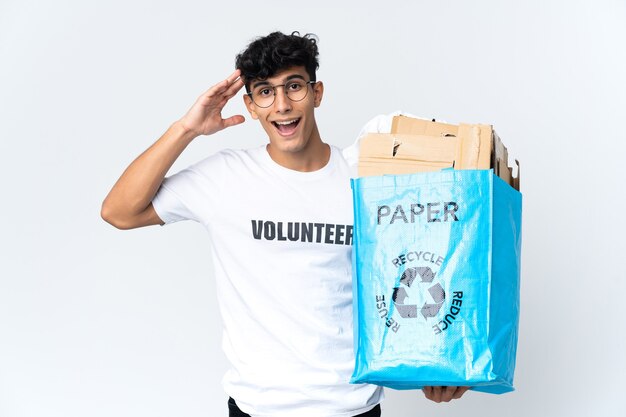 Jovem segurando uma sacola de reciclagem cheia de papel com expressão de surpresa