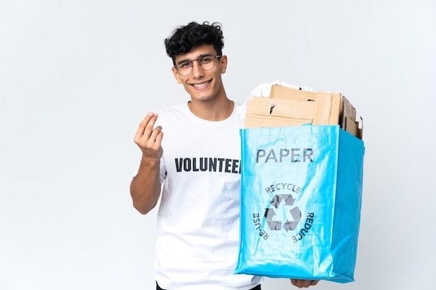 Jovem segurando uma sacola de reciclagem cheia de papel fazendo gesto de dinheiro