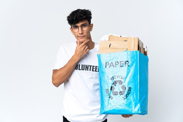 Jovem segurando uma sacola de reciclagem cheia de papel pensando