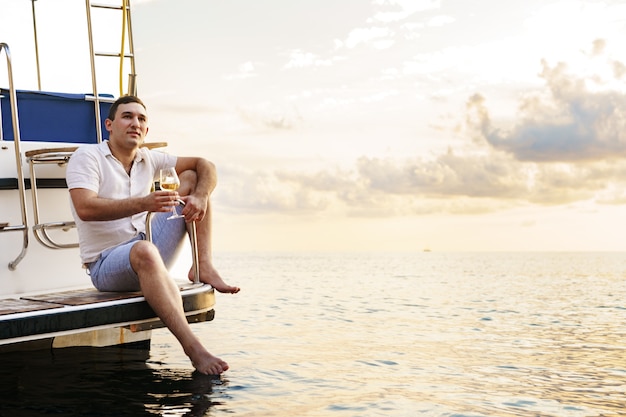 Foto jovem segurando uma taça de vinho no convés aberto de um barco de cruzeiro