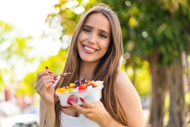 Jovem segurando uma tigela de frutas ao ar livre