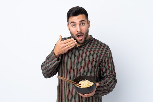 Jovem, segurando uma tigela de macarrão sobre parede isolada