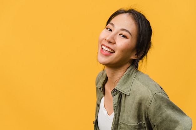 Foto jovem senhora asiática com expressão positiva, sorriso largo, vestida com roupas casuais sobre parede amarela. mulher feliz adorável feliz alegra sucesso. conceito de expressão facial.