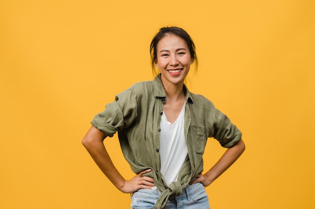 Foto jovem senhora asiática com expressão positiva, sorriso largo, vestida com roupas casuais sobre parede amarela. mulher feliz adorável feliz alegra sucesso. conceito de expressão facial.
