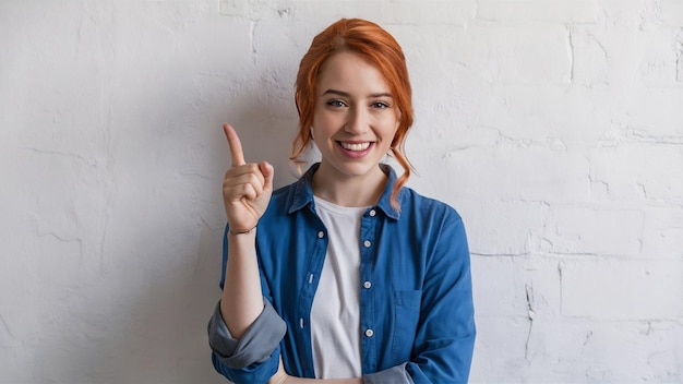 Foto jovem senhora com cabelos ruivos vestindo camisa azul e apontando o dedo para cima sorrindo como dando recomendação