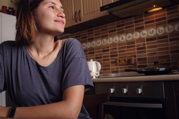 Jovem senta-se à mesa na cozinha