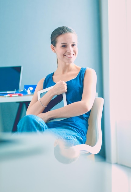 Jovem sentada à mesa com plano de instrumentos e laptop