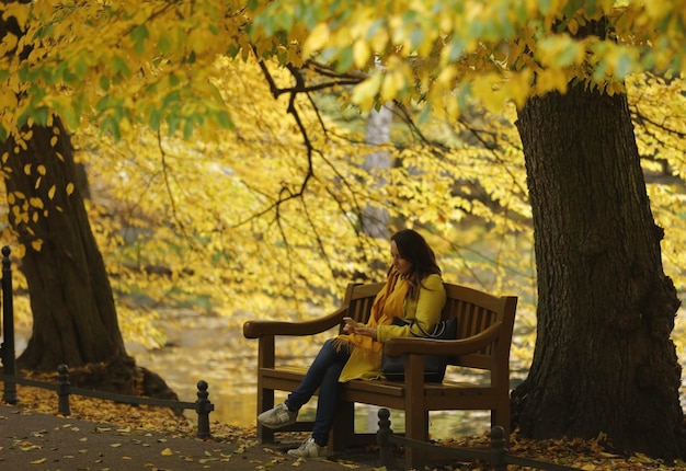 Foto jovem sentada em um banco no parque