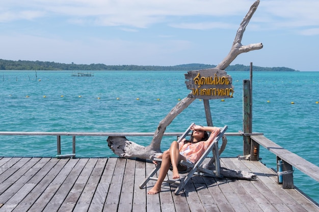 Jovem sentada em um berço em uma bela ponte de madeira em Koh Mak Trad Tailândia