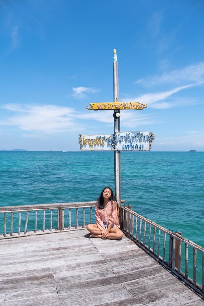 Jovem sentada em um berço em uma bela ponte de madeira em Koh Mak Trad Tailândia