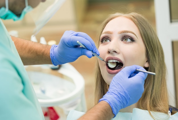 jovem sentada na cadeira do dentista com a boca aberta no consultório do dentista enquanto faz o exame.