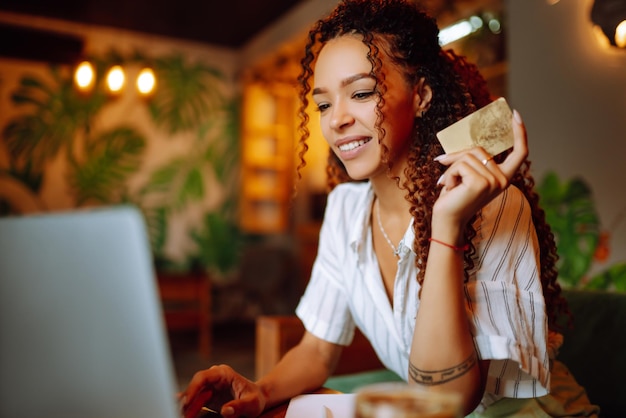 Foto jovem sentada no café fazendo compras online usando cartão de crédito e laptop compras online