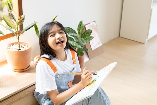 Jovem sentada no chão e pintando em papel em casa hobby e estudo de arte em casa