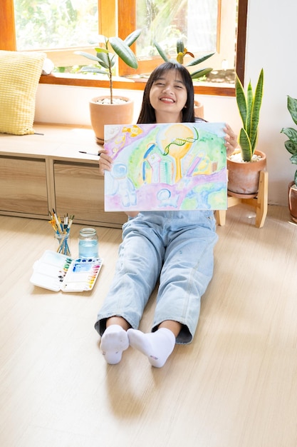 Jovem sentada no chão e pintando em papel em casa Hobby e estudo de arte em casa