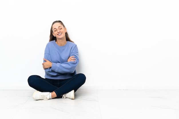 Jovem sentada no chão feliz e sorridente