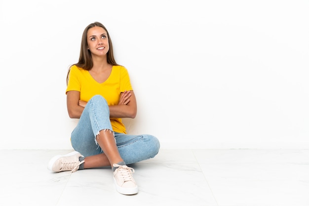 Jovem sentada no chão, olhando para cima enquanto sorri