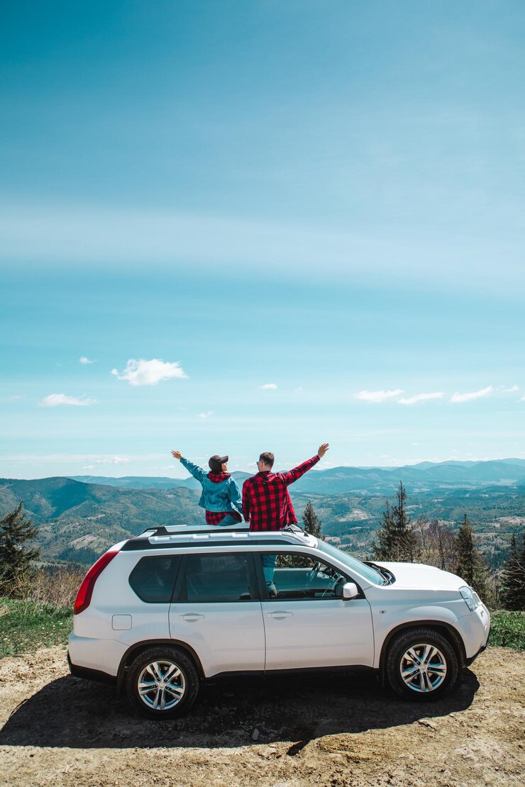 Foto jovem sentada no topo do carro suv no pico da montanha, apreciando a vista da paisagem