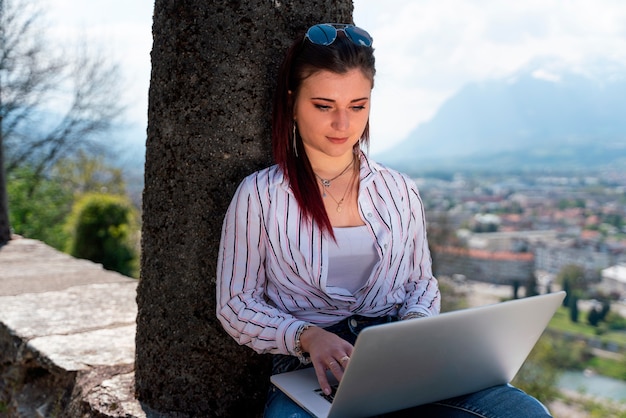 Jovem sentada trabalhando em seu laptop