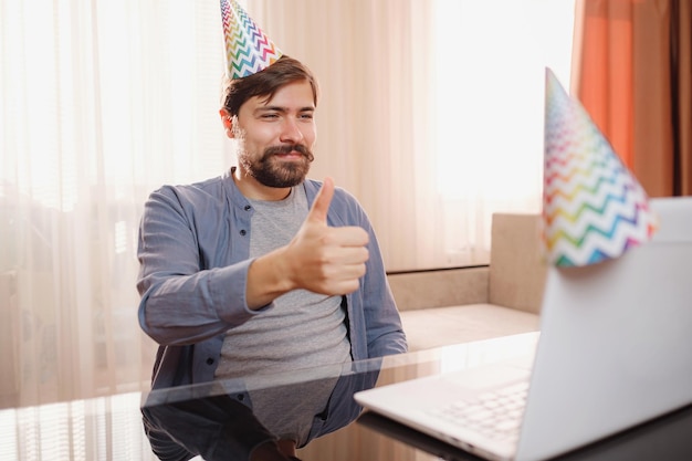 Foto jovem sentado à mesa e conversando por videochamada com amigos