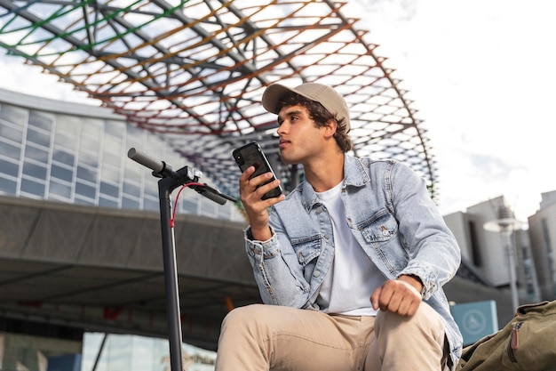 Foto jovem sentado ao lado de uma scooter