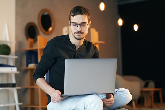 Jovem sentado com o computador. freelancer em copos trabalhando com laptop, gerente de projeto.