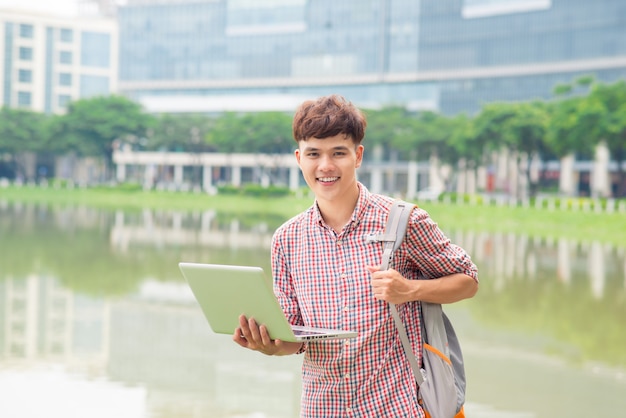 Jovem sentado com um laptop fora do escritório