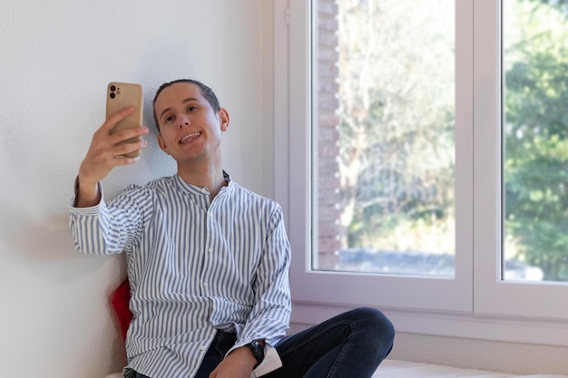 Jovem sentado e tirando uma selfie sorrindo e mostrando a língua