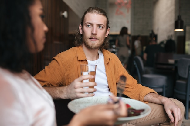 Jovem sentado em um restaurante conversando com uma mulher