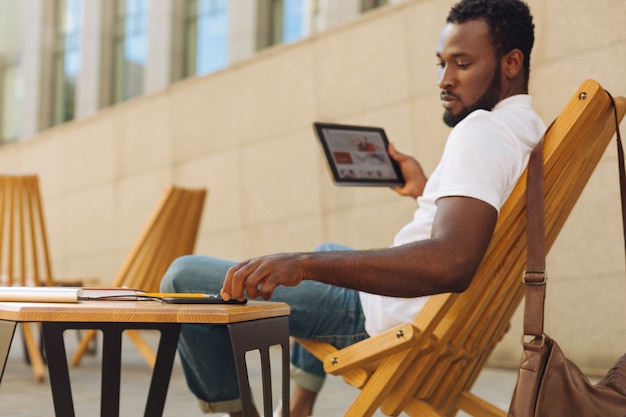 Jovem sentado em um terraço lendo um artigo