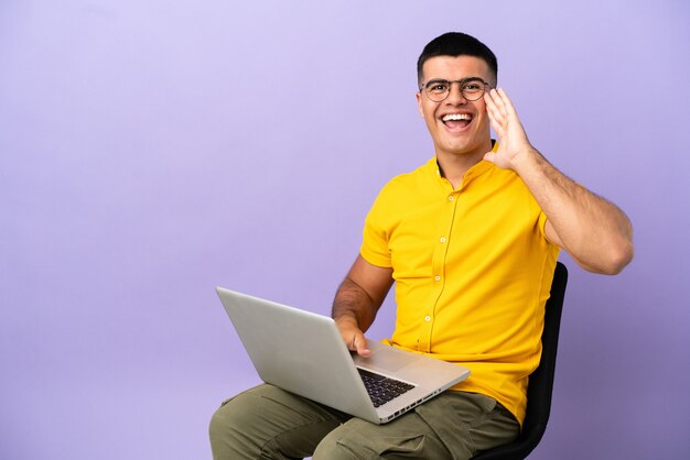 Jovem sentado em uma cadeira com laptop gritando com a boca bem aberta