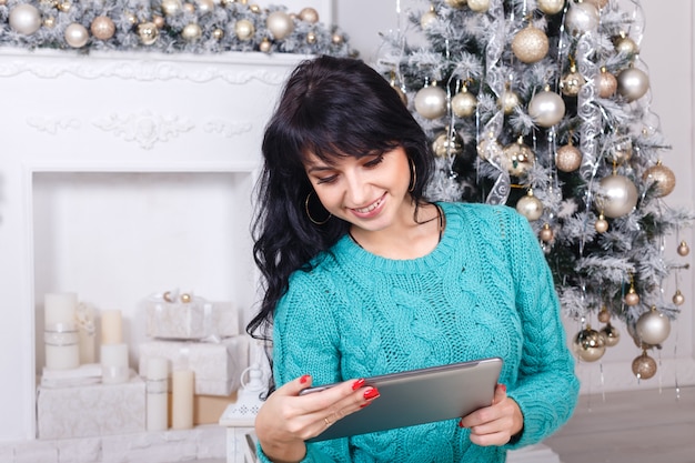 Jovem sentado em uma sala de estar com decoração de Natal usando um tablet