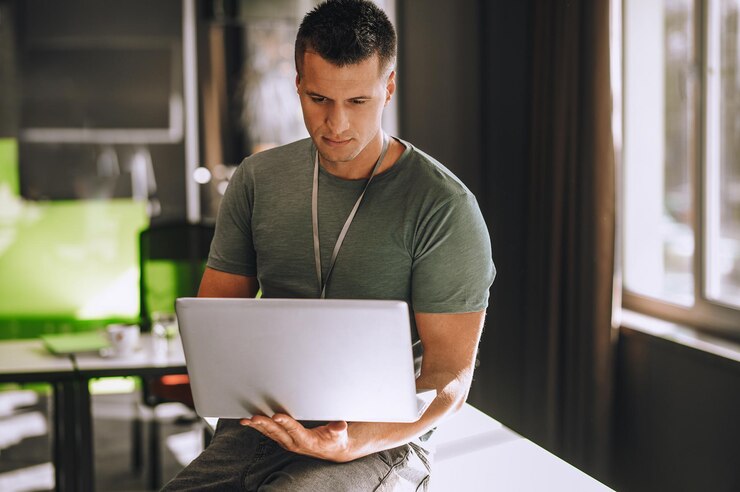 Foto jovem sentado na mesa com um laptop