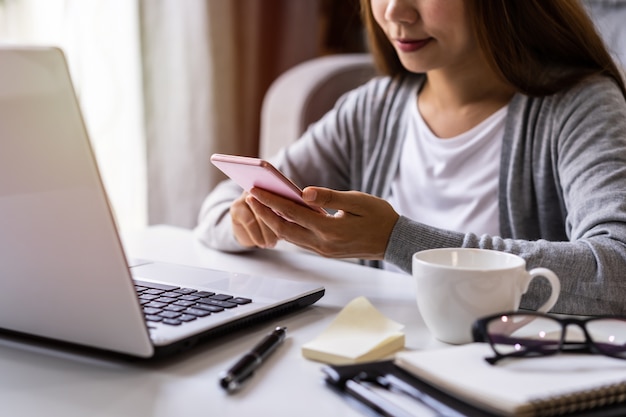 Jovem sentado na sala de estar e trabalhando no laptop e smartphone em casa