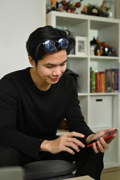 Jovem sentado na sala de estar e usando o celular