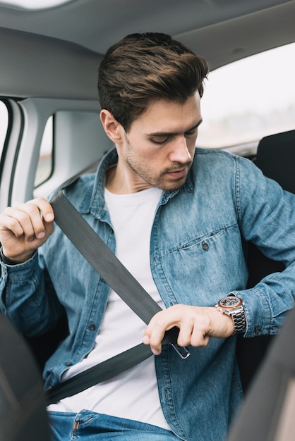 Foto jovem sentado no carro prende o cinto de segurança