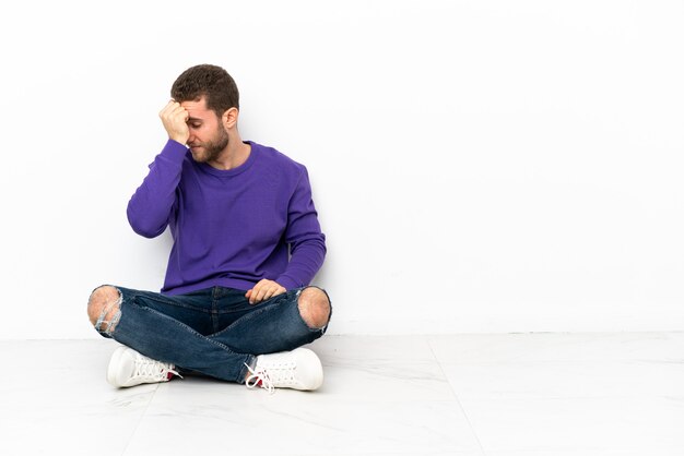 Jovem sentado no chão com dor de cabeça