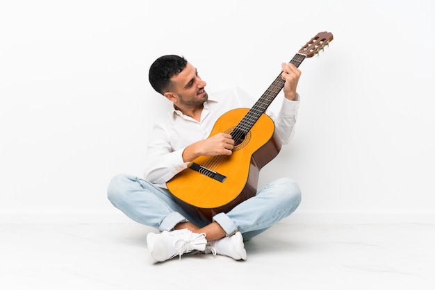 Jovem sentado no chão com guitarra