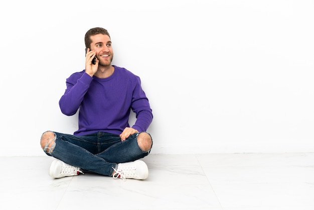 Jovem sentado no chão, conversando com o celular