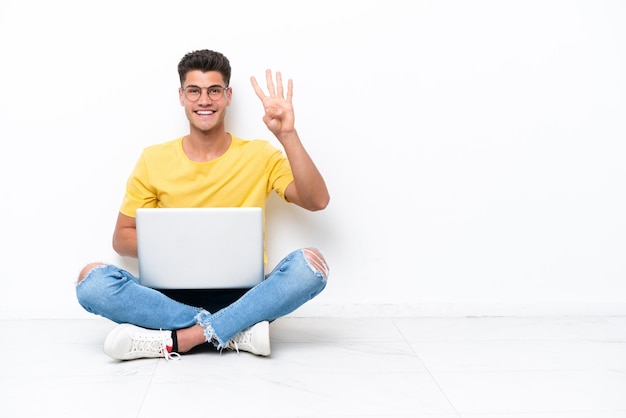 Jovem sentado no chão isolado no fundo branco feliz e contando quatro com os dedos